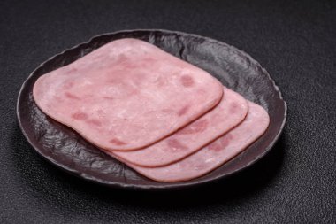 Tuzlu ve baharatlı haşlanmış jambon. Koyu beton arka planda dilimler halinde kesilmiş.