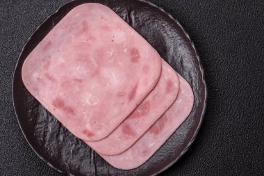 Tuzlu ve baharatlı haşlanmış jambon. Koyu beton arka planda dilimler halinde kesilmiş.