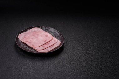 Tuzlu ve baharatlı haşlanmış jambon. Koyu beton arka planda dilimler halinde kesilmiş.