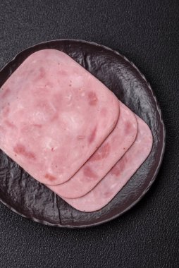 Tuzlu ve baharatlı haşlanmış jambon. Koyu beton arka planda dilimler halinde kesilmiş.