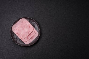 Tuzlu ve baharatlı haşlanmış jambon. Koyu beton arka planda dilimler halinde kesilmiş.