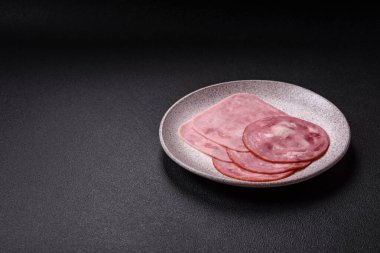 Tuzlu ve baharatlı haşlanmış jambon. Koyu beton arka planda dilimler halinde kesilmiş.