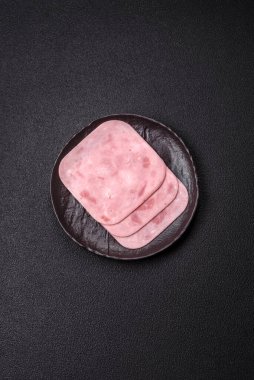 Tuzlu ve baharatlı haşlanmış jambon. Koyu beton arka planda dilimler halinde kesilmiş.