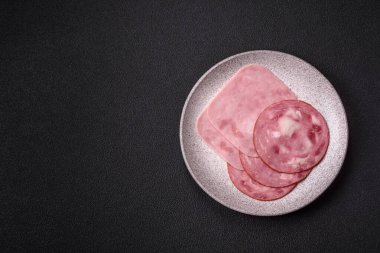 Tuzlu ve baharatlı haşlanmış jambon. Koyu beton arka planda dilimler halinde kesilmiş.