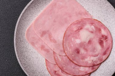 Tuzlu ve baharatlı haşlanmış jambon. Koyu beton arka planda dilimler halinde kesilmiş.