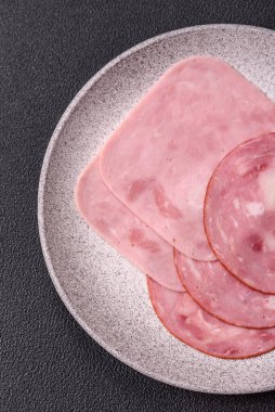 Tuzlu ve baharatlı haşlanmış jambon. Koyu beton arka planda dilimler halinde kesilmiş.