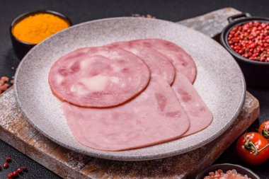 Tuzlu ve baharatlı haşlanmış jambon. Koyu beton arka planda dilimler halinde kesilmiş.