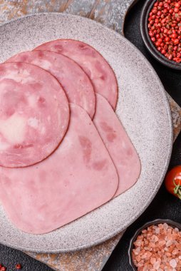 Tuzlu ve baharatlı haşlanmış jambon. Koyu beton arka planda dilimler halinde kesilmiş.