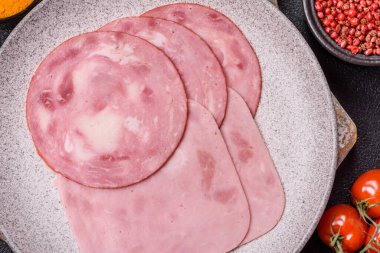 Tuzlu ve baharatlı haşlanmış jambon. Koyu beton arka planda dilimler halinde kesilmiş.