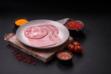 Tuzlu ve baharatlı haşlanmış jambon. Koyu beton arka planda dilimler halinde kesilmiş.