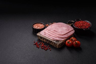 Tuzlu ve baharatlı haşlanmış jambon. Koyu beton arka planda dilimler halinde kesilmiş.