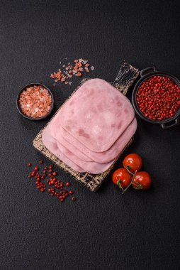 Tuzlu ve baharatlı haşlanmış jambon. Koyu beton arka planda dilimler halinde kesilmiş.