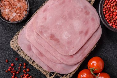 Tuzlu ve baharatlı haşlanmış jambon. Koyu beton arka planda dilimler halinde kesilmiş.