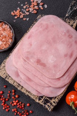 Tuzlu ve baharatlı haşlanmış jambon. Koyu beton arka planda dilimler halinde kesilmiş.