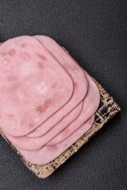 Tuzlu ve baharatlı haşlanmış jambon. Koyu beton arka planda dilimler halinde kesilmiş.