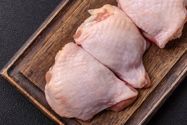 Taze çiğ tavuk butları, koyu beton arka planda tuz ve baharatlar.