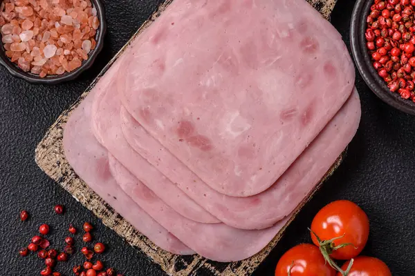 Tuzlu ve baharatlı haşlanmış jambon. Koyu beton arka planda dilimler halinde kesilmiş.