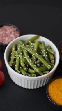 Zeytin yağı, susam tohumu, tuz ve baharatlı bir tabakta haşlanmış yeşil fasulye.