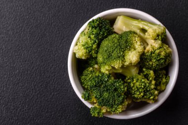 Lezzetli taze brokoli, dokulu beton arka planda seramik bir tabakta buğulanmış.