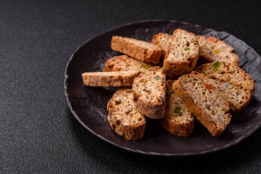 Taze pişmiş İtalyan cantuccini kurabiyeleri fındıklı ve şekerli meyveler koyu beton arka planda