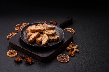 Taze pişmiş İtalyan cantuccini kurabiyeleri fındıklı ve şekerli meyveler koyu beton arka planda