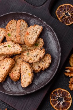Taze pişmiş İtalyan cantuccini kurabiyeleri fındıklı ve şekerli meyveler koyu beton arka planda