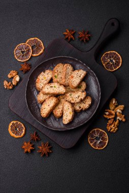 Taze pişmiş İtalyan cantuccini kurabiyeleri fındıklı ve şekerli meyveler koyu beton arka planda