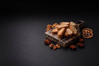 Taze pişmiş İtalyan cantuccini kurabiyeleri fındıklı ve şekerli meyveler koyu beton arka planda