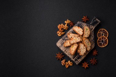 Taze pişmiş İtalyan cantuccini kurabiyeleri fındıklı ve şekerli meyveler koyu beton arka planda