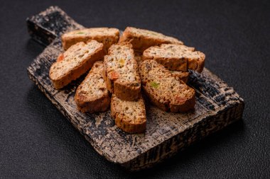 Taze pişmiş İtalyan cantuccini kurabiyeleri fındıklı ve şekerli meyveler koyu beton arka planda