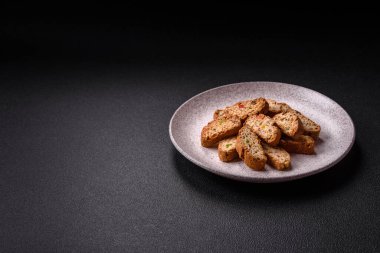 Taze pişmiş İtalyan cantuccini kurabiyeleri fındıklı ve şekerli meyveler koyu beton arka planda