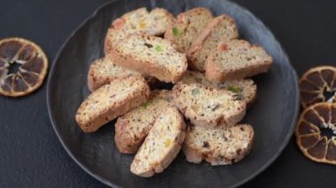 Taze pişmiş İtalyan cantuccini kurabiyeleri fındıklı ve şekerli meyveler koyu beton arka planda