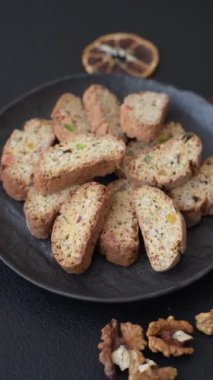 Taze pişmiş İtalyan cantuccini kurabiyeleri fındıklı ve şekerli meyveler koyu beton arka planda