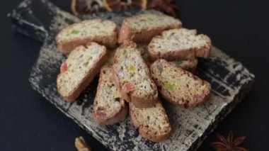 Taze pişmiş İtalyan cantuccini kurabiyeleri fındıklı ve şekerli meyveler koyu beton arka planda