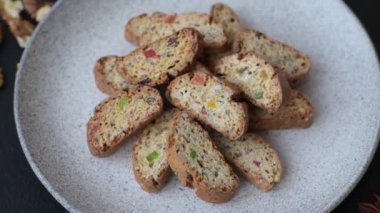 Taze pişmiş İtalyan cantuccini kurabiyeleri fındıklı ve şekerli meyveler koyu beton arka planda