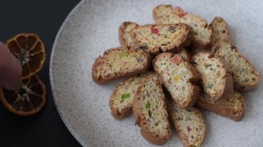 Taze pişmiş İtalyan cantuccini kurabiyeleri fındıklı ve şekerli meyveler koyu beton arka planda