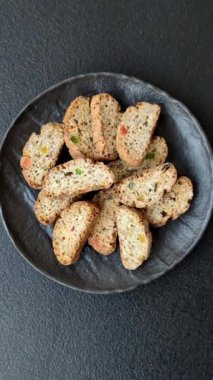 Taze pişmiş İtalyan cantuccini kurabiyeleri fındıklı ve şekerli meyveler koyu beton arka planda