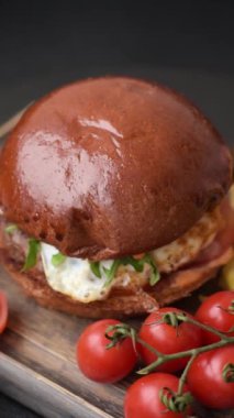Köfteli lezzetli burger, kızarmış yumurta, pastırma, otlar, sos, tuz ve baharatlar koyu beton arka planda.