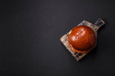 Köfteli lezzetli burger, kızarmış yumurta, pastırma, otlar, sos, tuz ve baharatlar koyu beton arka planda.