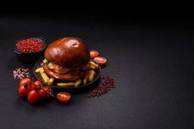 Köfteli lezzetli burger, kızarmış yumurta, pastırma, otlar, sos, tuz ve baharatlar koyu beton arka planda.