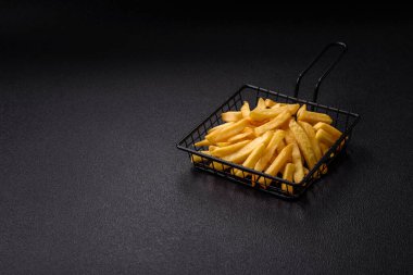 Koyu beton arka planda tuz ve baharatlı çıtır patates kızartması.