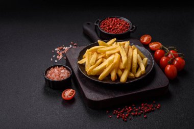 Koyu beton arka planda tuz ve baharatlı çıtır patates kızartması.
