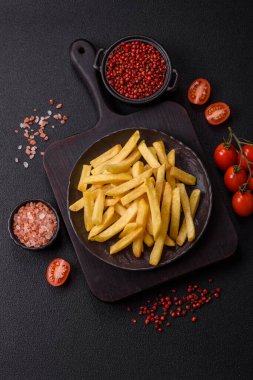 Koyu beton arka planda tuz ve baharatlı çıtır patates kızartması.