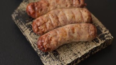 Koyu beton bir arka planda ızgarada tuzlu ve baharatlı sulu tavuk ya da domuz sosisi.