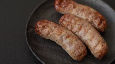 Koyu beton bir arka planda ızgarada tuzlu ve baharatlı sulu tavuk ya da domuz sosisi.