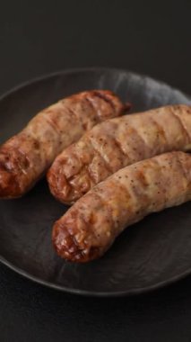 Koyu beton bir arka planda ızgarada tuzlu ve baharatlı sulu tavuk ya da domuz sosisi.