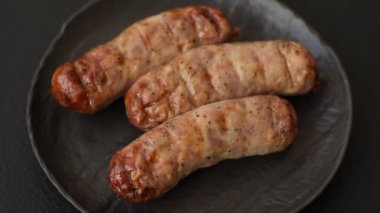 Koyu beton bir arka planda ızgarada tuzlu ve baharatlı sulu tavuk ya da domuz sosisi.