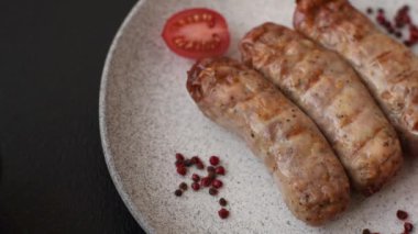 Koyu beton bir arka planda ızgarada tuzlu ve baharatlı sulu tavuk ya da domuz sosisi.