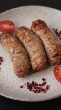 Koyu beton bir arka planda ızgarada tuzlu ve baharatlı sulu tavuk ya da domuz sosisi.