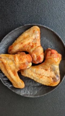 Koyu beton arka planda tuzlu ve baharatlı ızgara tavuk kanadı.